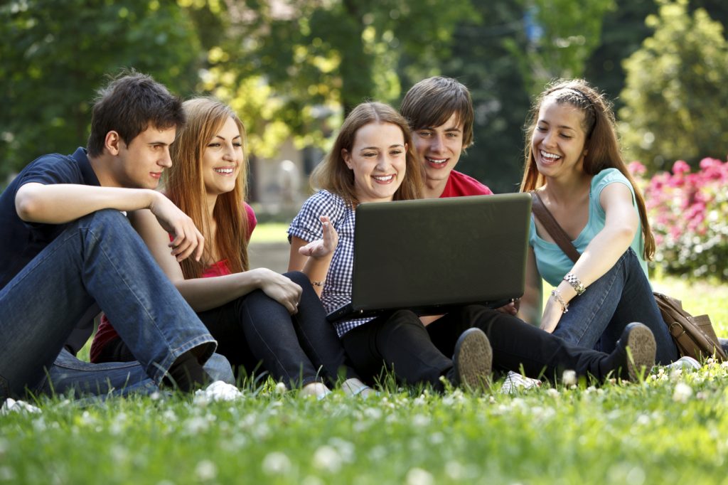 Group of college students using laptop outdoors