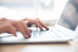 Close-up of male hands typing on laptop keyboard indoors. Businessman working in office or student browsing information