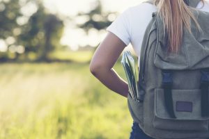 Hiking woman with backpack walking on a gravel road